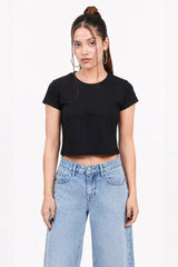 Woman wearing a black crop top and light blue jeans on a white background.black crop top, black crop top women, women's black crop top, black top for women, trendy black crop top, stylish black crop top, casual black crop top, fitted crop top, cropped top women, sleeveless black top, black fashion top, women's fashion top, ladies black top, black crop tank top, summer crop top, trendy women's clothing, casual women's wear, street style outfit, black crop top outfit, blue jeans outfit.
