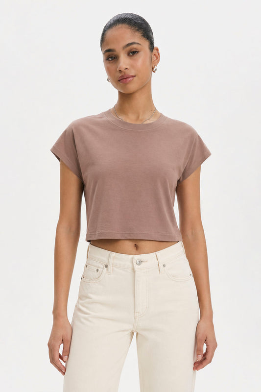 Woman wearing a brown cropped t-shirt and white pants on a plain background. brown cotton crop top. aesthetic fashion top. Comfortable cotton crop top in latte brown shade.Basic brown crop top for casual and layered outfits. Trendy brown cotton crop top for women’s fashion store. Soft stretch cotton brown crop top for daily wear. Brown fitted crop top with clean minimal design. Cotton cap sleeve crop top in earthy brown tone.
Women’s latte brown cropped cotton t-shirt top. Casual chic brown cotton crop top