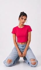 Woman wearing a red crop top and light blue jeans on a white background.ink crop top, hot pink top, dark pink crop top, crop top in pink, pink crop top women, h&m pink top, crop top trend, trending crop top, pink top, crop top girls.women top, a woman wearing pink crop top, collegdge outfit ideas,women pink top, girl pink top.
