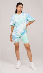 Person wearing a tie-dye outfit with a t-shirt and shorts on a plain background