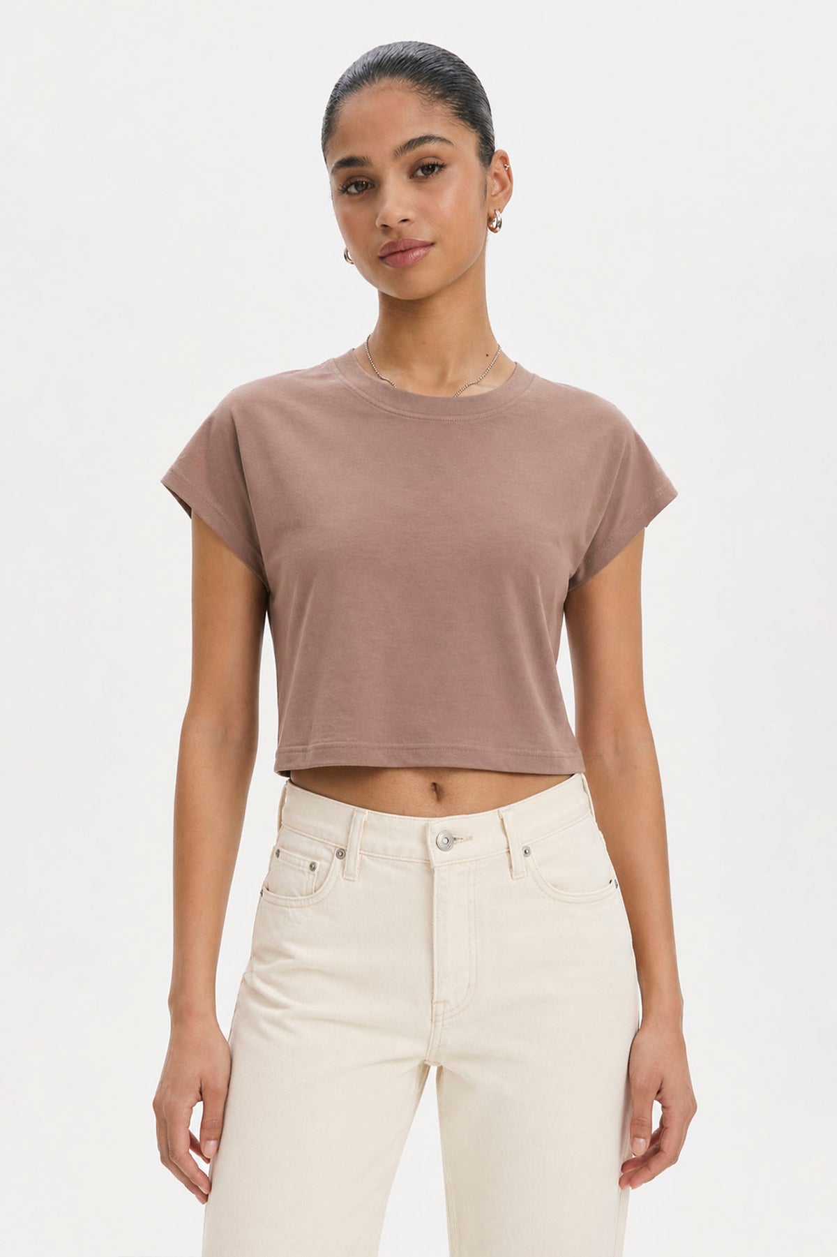 Woman wearing a brown cropped t-shirt and white pants on a plain background. brown cotton crop top. aesthetic fashion top. Comfortable cotton crop top in latte brown shade.Basic brown crop top for casual and layered outfits. Trendy brown cotton crop top for women’s fashion store. Soft stretch cotton brown crop top for daily wear. Brown fitted crop top with clean minimal design. Cotton cap sleeve crop top in earthy brown tone.
Women’s latte brown cropped cotton t-shirt top. Casual chic brown cotton crop top 