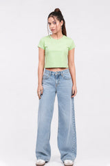 Woman wearing a light green crop top and blue jeans on a white background