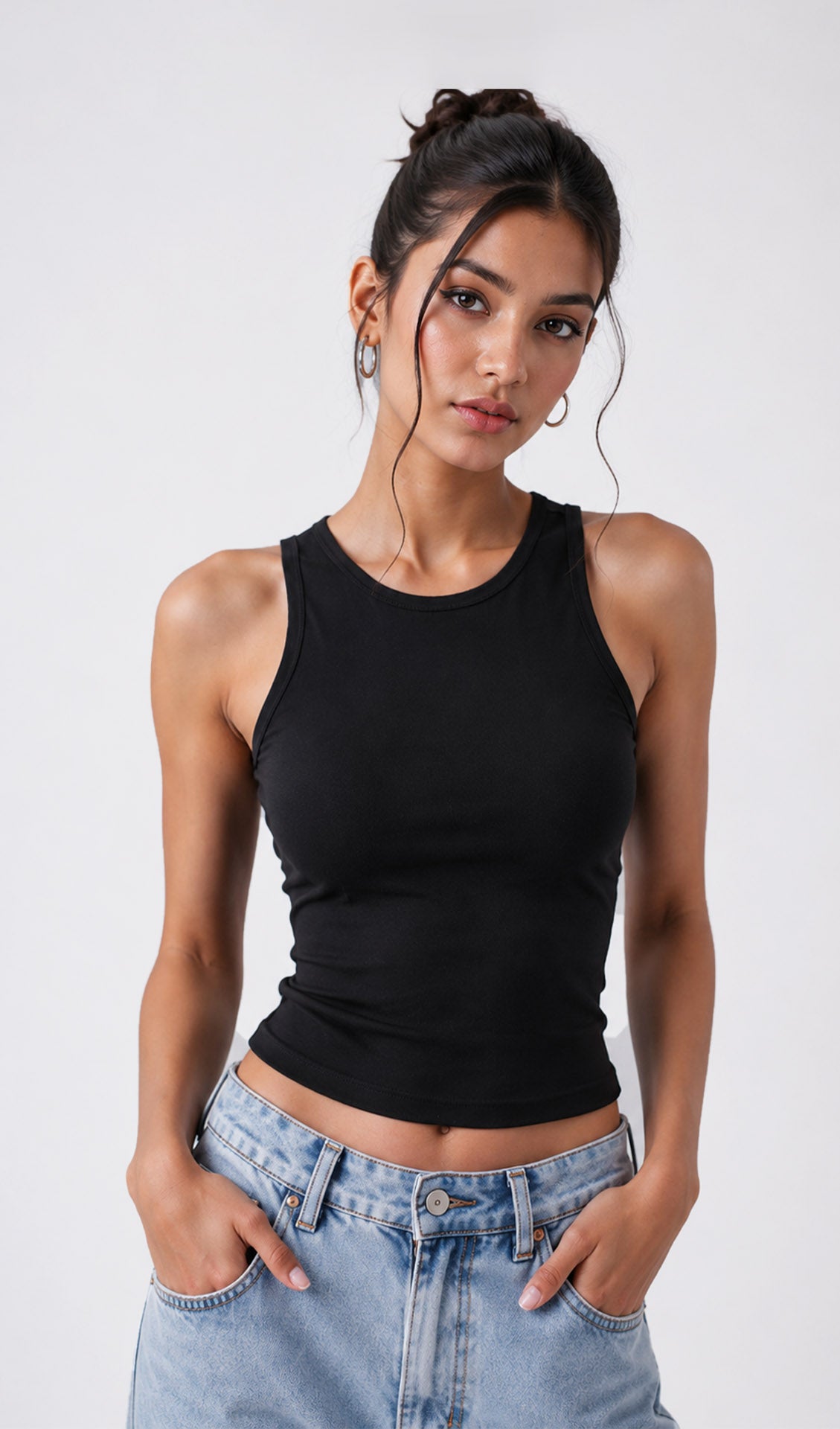 Woman wearing a black tank top and light blue jeans against a white background.black tank top, black tank top women, women's black tank top, black sleeveless top, black camisole top, black vest top women, black summer top, basic black tank top, fitted black tank top, ribbed black tank top, casual black top, trendy black tank top, women's fashion top, black top for women, ladies black top, stylish black tank top, black crop tank top, everyday tank top, minimalist fashion, casual women's wear, summer fashion 