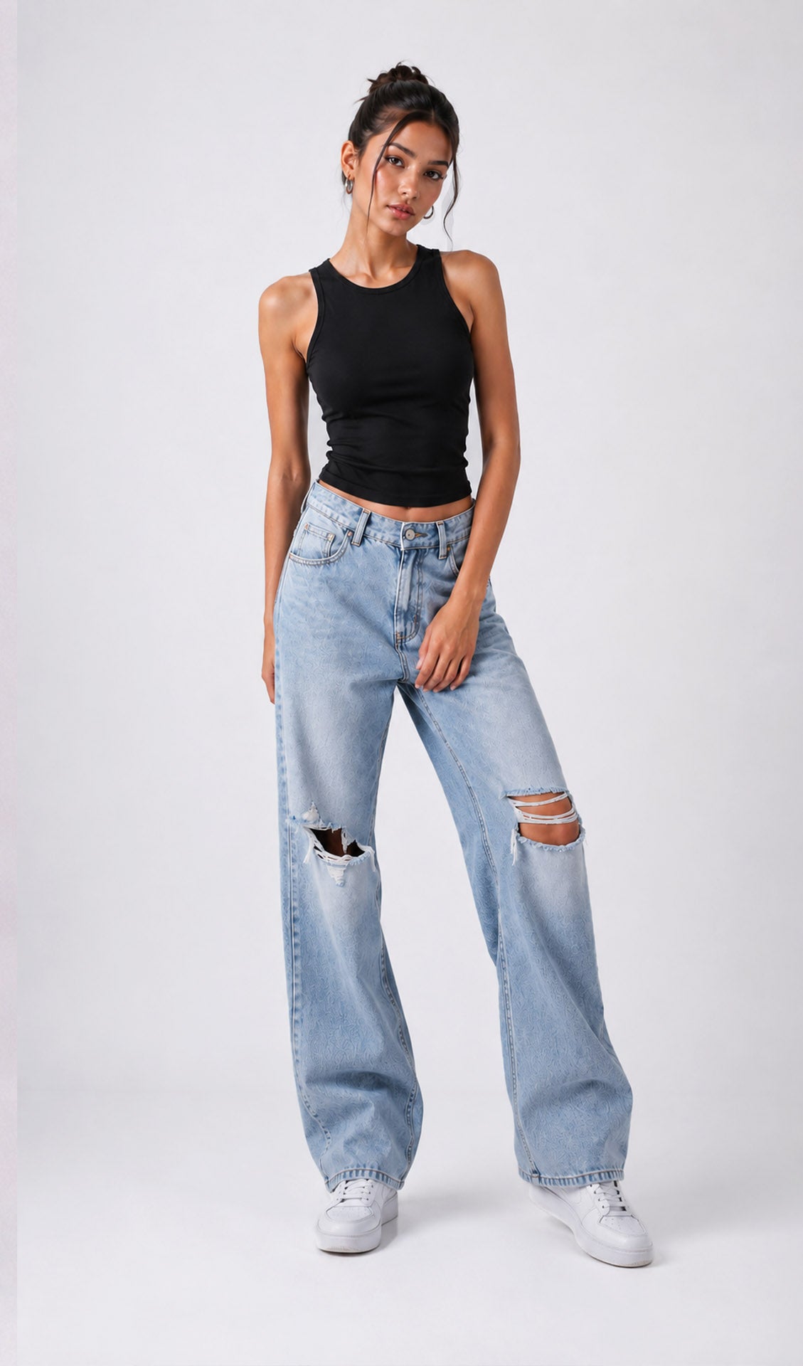 Woman wearing a black tank top and light blue jeans with rips on a white background.black tank top, black tank top women, women's black tank top, black sleeveless top, black camisole top, black vest top women, black summer top, basic black tank top, fitted black tank top, ribbed black tank top, casual black top, trendy black tank top, women's fashion top, black top for women, ladies black top, stylish black tank top, black crop tank top, everyday tank top, minimalist fashion, casual women's wear.